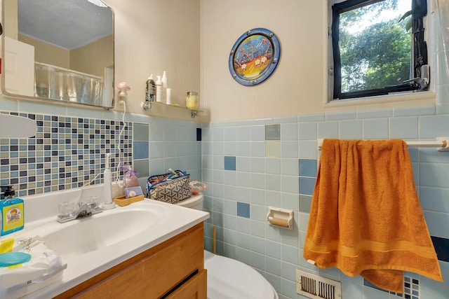 bathroom with tile walls, vanity, and toilet