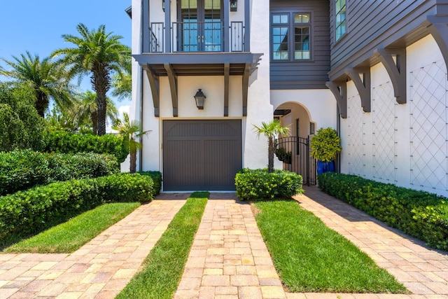 view of exterior entry with a balcony and a garage