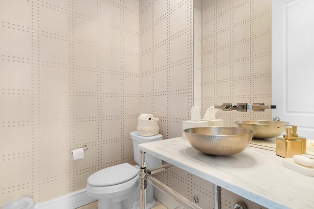 bathroom with toilet, tile walls, and sink