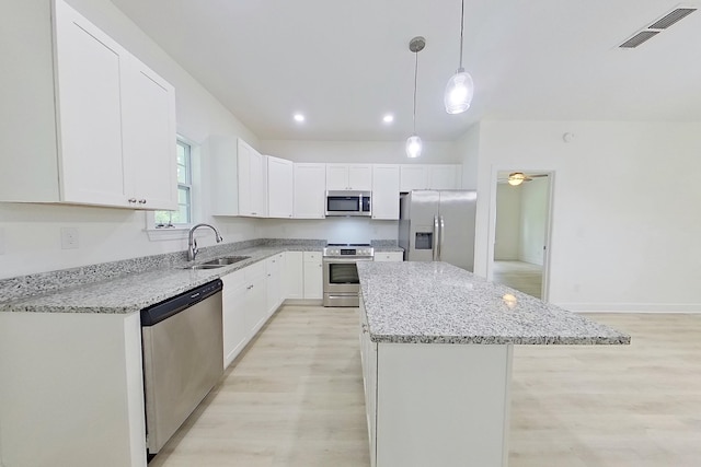 103 Heather Ln, Thomasville, GA 31792 - kitchen with appliances with stainless steel finishes, a sink, light wood-type flooring, a center island, and light stone counters