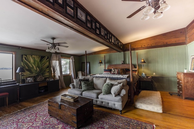 bedroom with lofted ceiling with beams, wooden walls, and wood finished floors