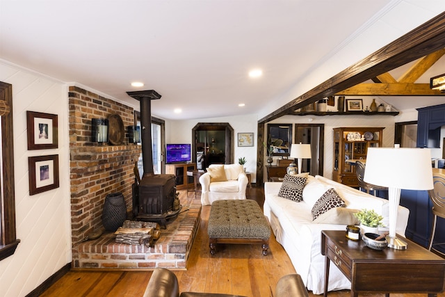 living area with recessed lighting, wood finished floors, a wood stove, and ornamental molding