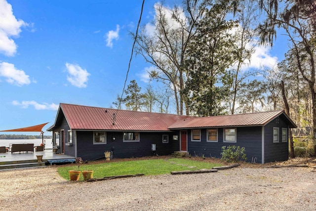 ranch-style home with a deck, metal roof, and a front yard