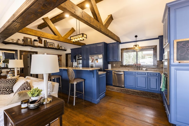 kitchen with blue cabinetry, a breakfast bar, light countertops, appliances with stainless steel finishes, and a sink