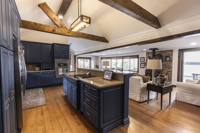 kitchen featuring a kitchen island, a wood stove, stainless steel appliances, blue cabinets, and open floor plan