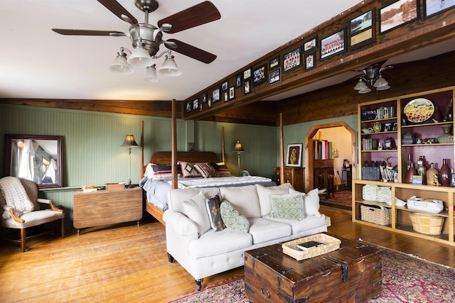 bedroom featuring arched walkways and wood finished floors