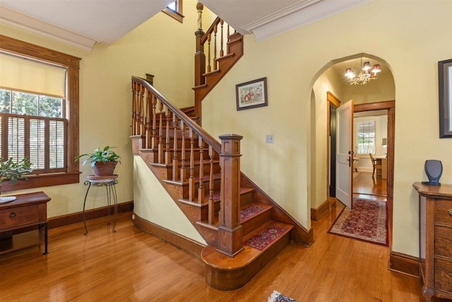 stairway featuring hardwood / wood-style floors, an inviting chandelier, and crown molding