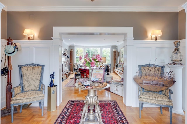 living area with a wainscoted wall, crown molding, and a decorative wall