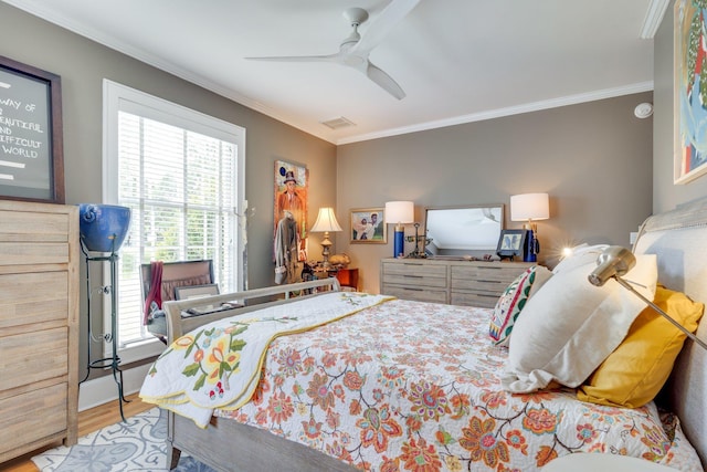 bedroom featuring wood finished floors, crown molding, visible vents, and a ceiling fan
