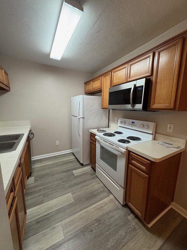 2525 Hartsfield Rd Unit 9, Tallahassee, FL 32303 - kitchen featuring white appliances, light wood-type flooring, light countertops, and brown cabinets