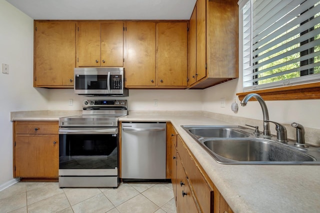 3268 Garcia Dr, Tallahassee, FL 32309 - kitchen featuring appliances with stainless steel finishes, a sink, light tile patterned floors, light countertops, and brown cabinetry
