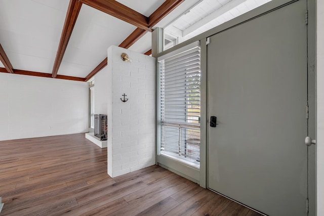 foyer with a brick fireplace, vaulted ceiling with beams, and light hardwood / wood-style floors