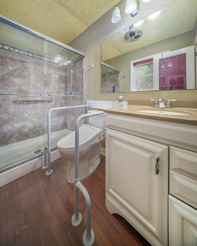 bathroom featuring walk in shower, toilet, wood-type flooring, a textured ceiling, and vanity