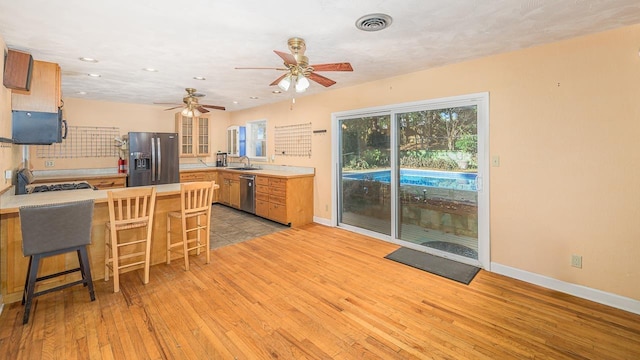 kitchen with sink, stainless steel appliances, kitchen peninsula, and light wood-type flooring