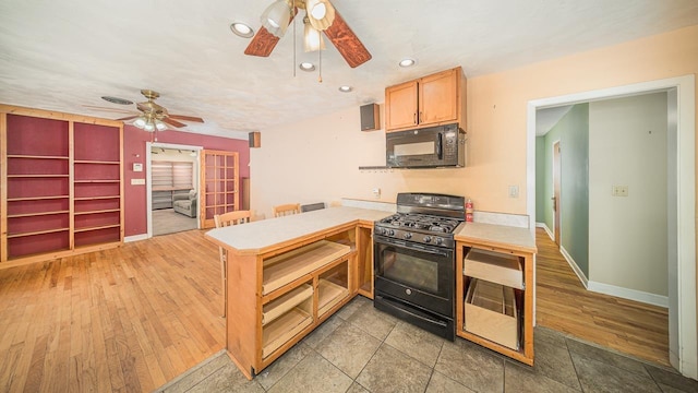 kitchen featuring light hardwood / wood-style flooring, black appliances, kitchen peninsula, and ceiling fan