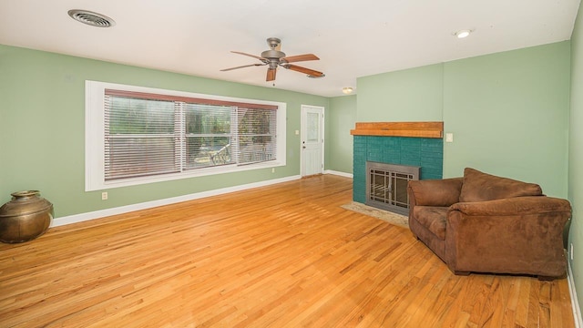 living room featuring ceiling fan, a fireplace, and light hardwood / wood-style flooring