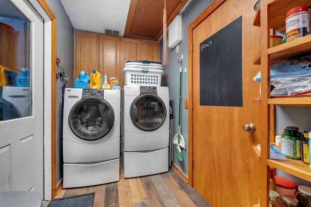 laundry room with independent washer and dryer, cabinets, and light hardwood / wood-style floors