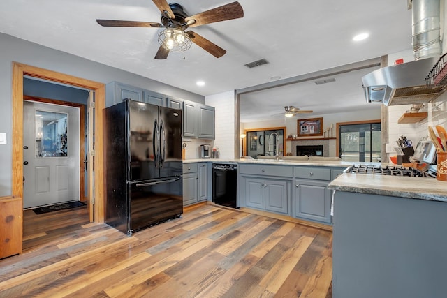 kitchen with black appliances, gray cabinetry, island exhaust hood, kitchen peninsula, and light wood-type flooring