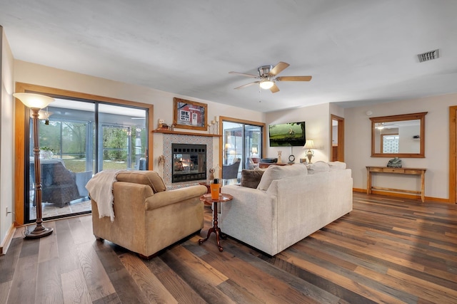 living room with ceiling fan, dark hardwood / wood-style floors, and a tiled fireplace