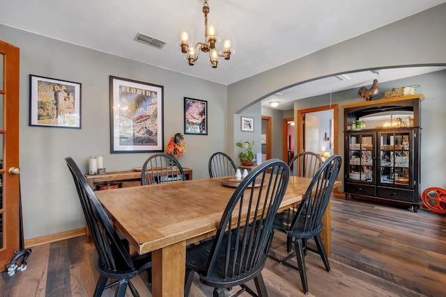 dining room with dark hardwood / wood-style floors and an inviting chandelier