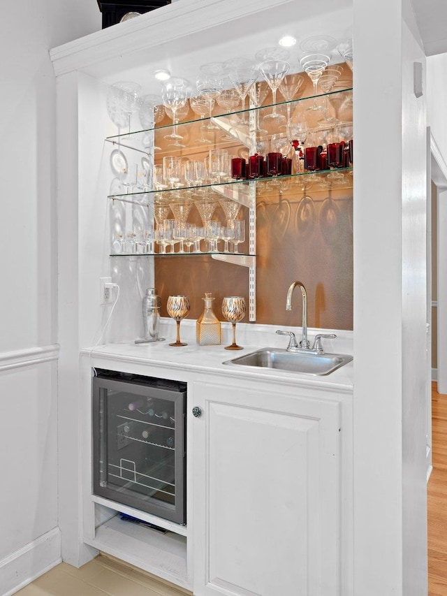 bar with white cabinetry, beverage cooler, and sink