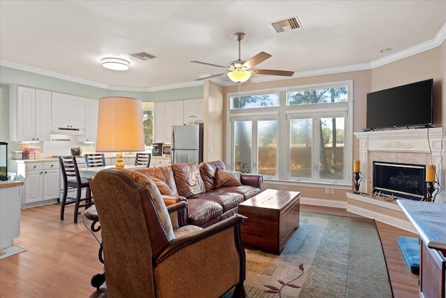 living room with crown molding, ceiling fan, and light wood-type flooring