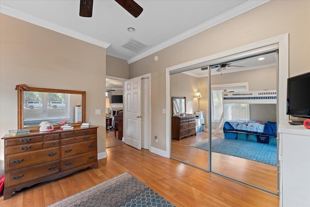 bedroom featuring crown molding, ceiling fan, a closet, and light wood-type flooring