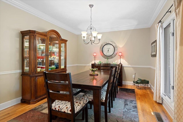 dining space with crown molding, a chandelier, and light wood-type flooring