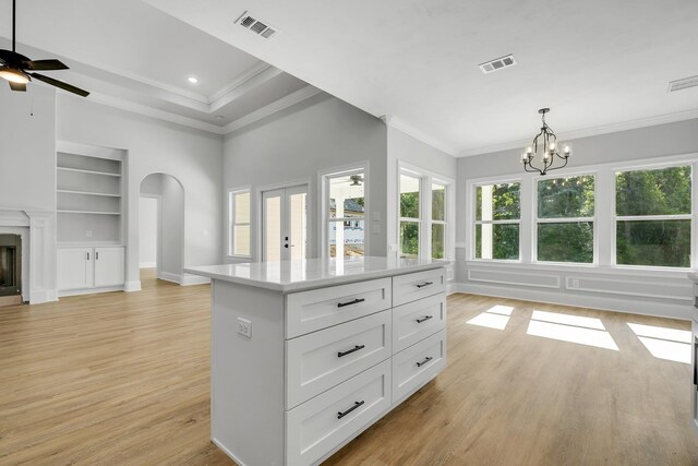 kitchen featuring visible vents, built in features, open floor plan, light wood-style flooring, and ceiling fan with notable chandelier