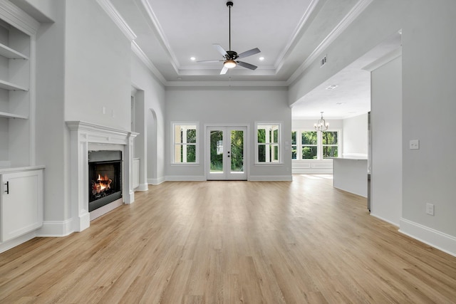 unfurnished living room with a towering ceiling, crown molding, ceiling fan with notable chandelier, light wood finished floors, and a premium fireplace