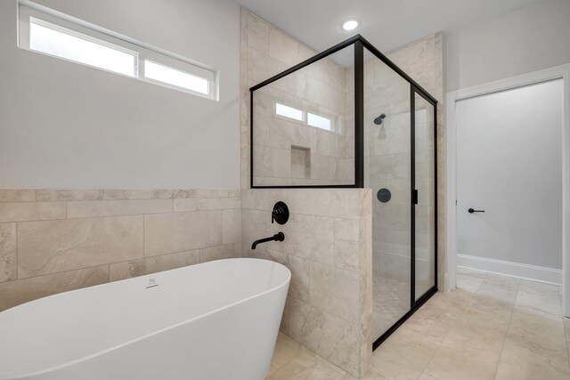 bathroom featuring a freestanding bath, marble finish floor, and a stall shower