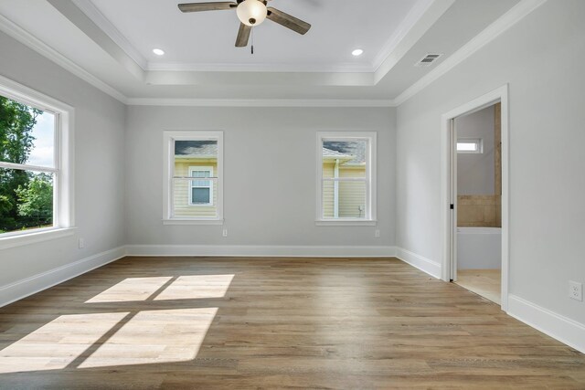 empty room with visible vents, a raised ceiling, ceiling fan, and light wood-style floors