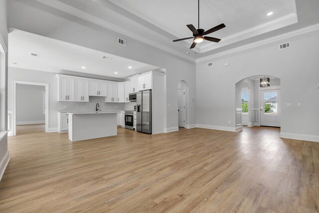 unfurnished living room featuring arched walkways, a ceiling fan, visible vents, and a raised ceiling