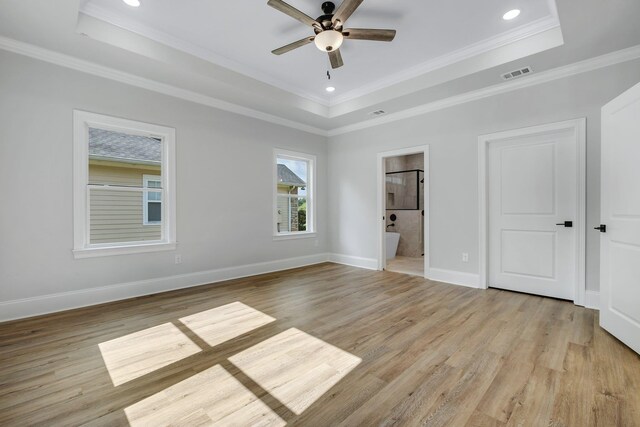 unfurnished bedroom featuring visible vents, a tray ceiling, and light wood-type flooring
