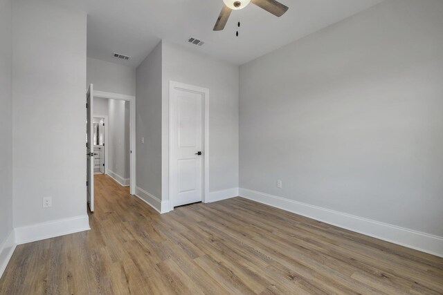 unfurnished bedroom featuring a ceiling fan, baseboards, visible vents, and wood finished floors