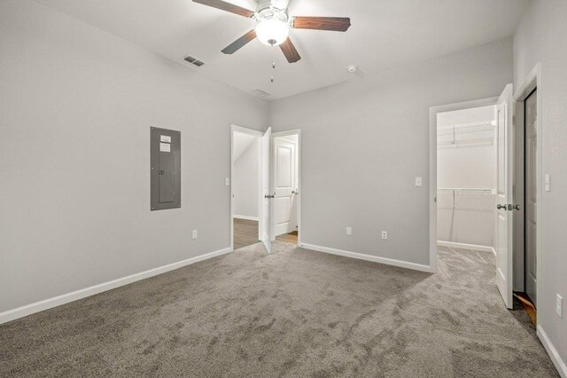 unfurnished bedroom with electric panel, carpet, ceiling fan, a closet, and a spacious closet