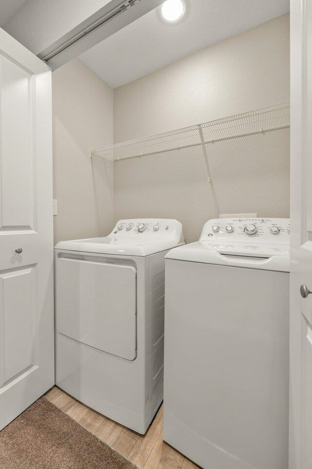 laundry room featuring light wood-type flooring and washing machine and clothes dryer