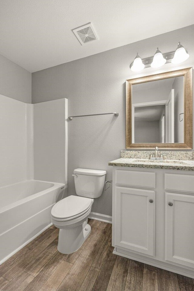 full bathroom with hardwood / wood-style flooring, vanity, toilet, and shower / bath combination