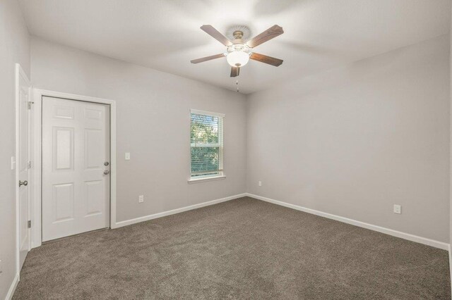 empty room featuring dark colored carpet and ceiling fan