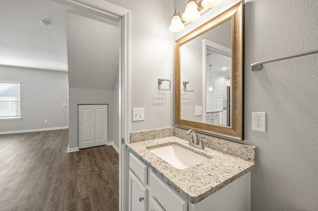 bathroom with hardwood / wood-style floors, vanity, and lofted ceiling