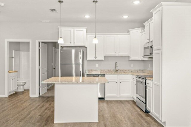 kitchen with pendant lighting, light hardwood / wood-style floors, appliances with stainless steel finishes, and white cabinets