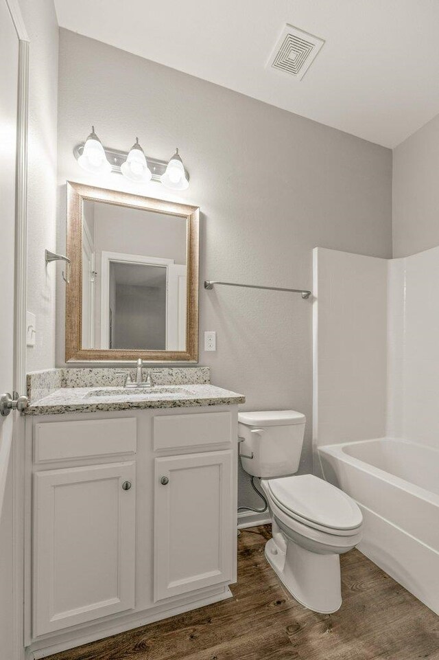 full bathroom featuring shower / washtub combination, vanity, hardwood / wood-style flooring, and toilet