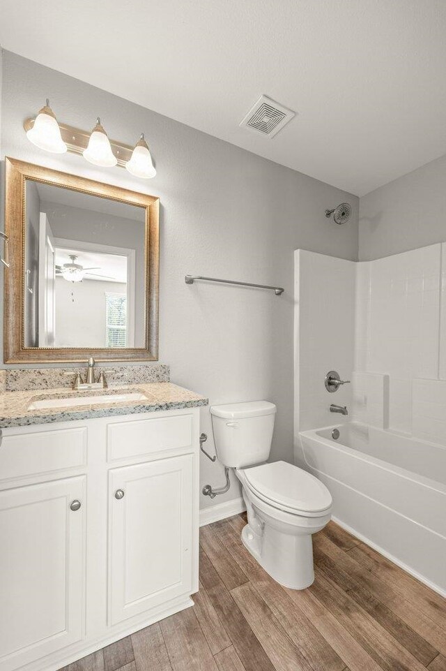 full bathroom featuring hardwood / wood-style floors, vanity, toilet, and shower / bathtub combination