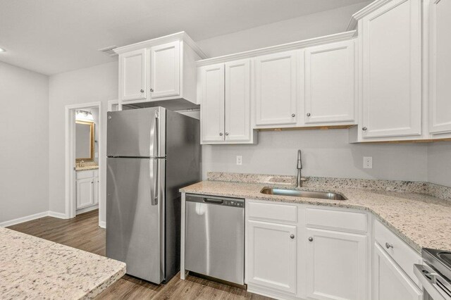 kitchen featuring stainless steel appliances, white cabinetry, light stone countertops, sink, and light hardwood / wood-style floors