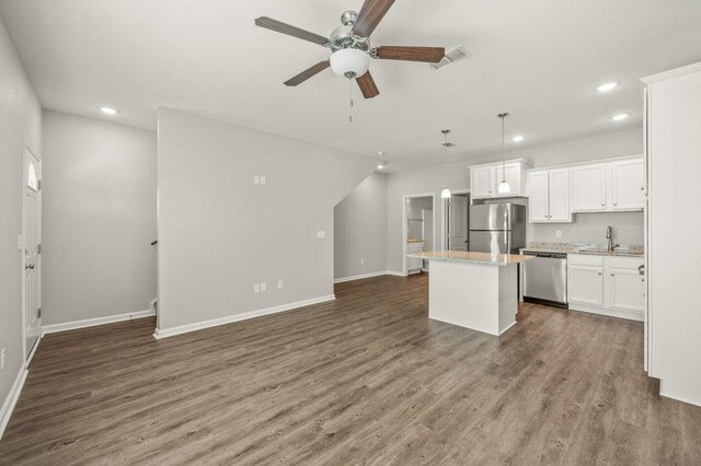 kitchen featuring wood-type flooring, hanging light fixtures, a kitchen island, white cabinetry, and appliances with stainless steel finishes