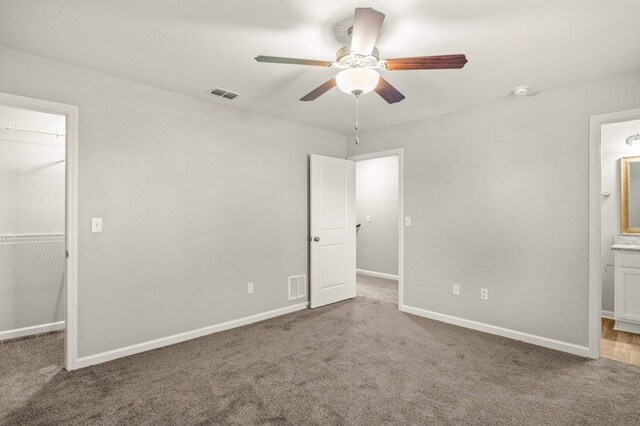 unfurnished bedroom featuring connected bathroom, carpet flooring, and ceiling fan