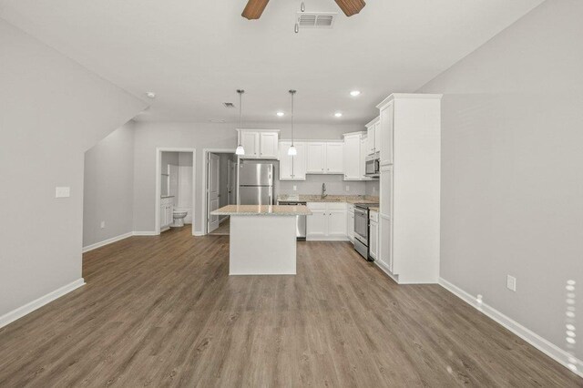 kitchen featuring light hardwood / wood-style floors, white cabinetry, appliances with stainless steel finishes, a kitchen island, and pendant lighting