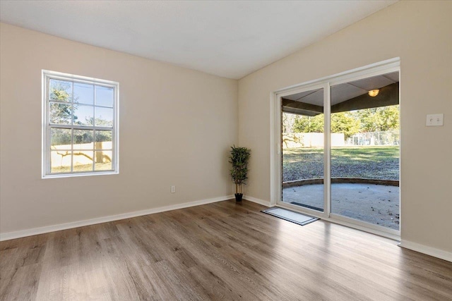 spare room with hardwood / wood-style floors and lofted ceiling