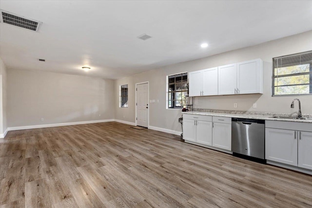 kitchen with stainless steel dishwasher, white cabinets, sink, and light hardwood / wood-style flooring