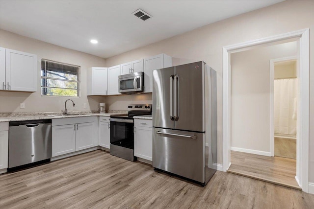 kitchen featuring sink, white cabinets, light hardwood / wood-style floors, and appliances with stainless steel finishes